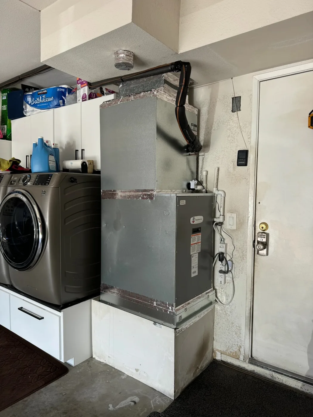 Furnace and air handler cabinet installed in a garage next to the laundry