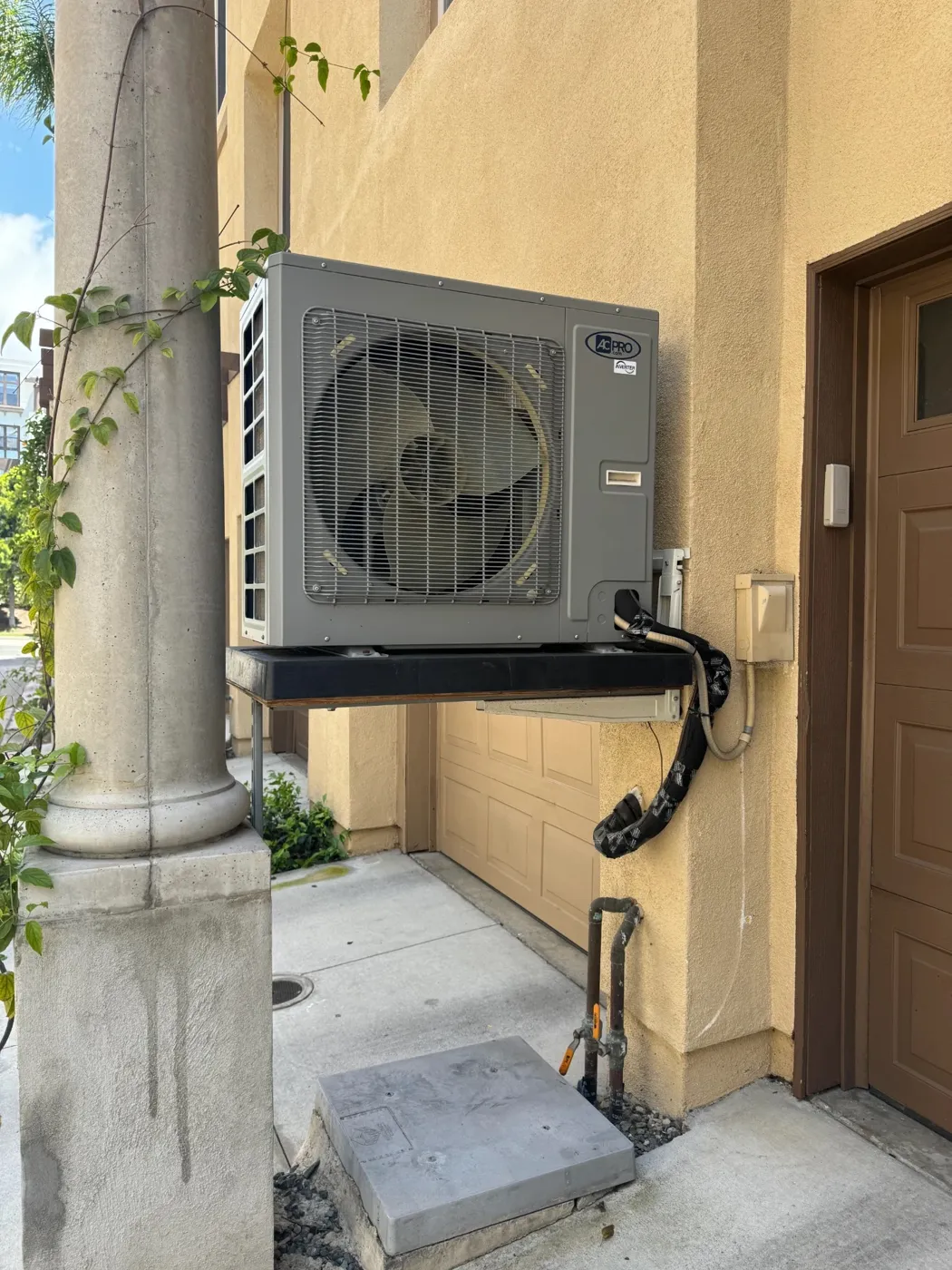 Side discharge heat pump mounted on a wall bracket at a San Diego townhome