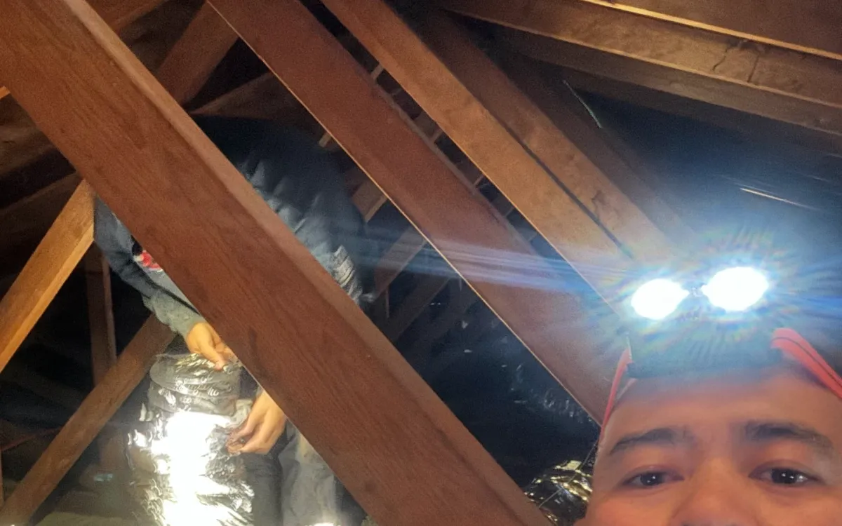 Attic workspace lit up during a whole house fan installation